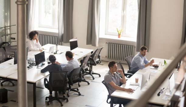 Top view of diverse people working together on computer performing daily routine tasks in coworking space, multiracial millennial men and women busy using devices discussing projects in shared office